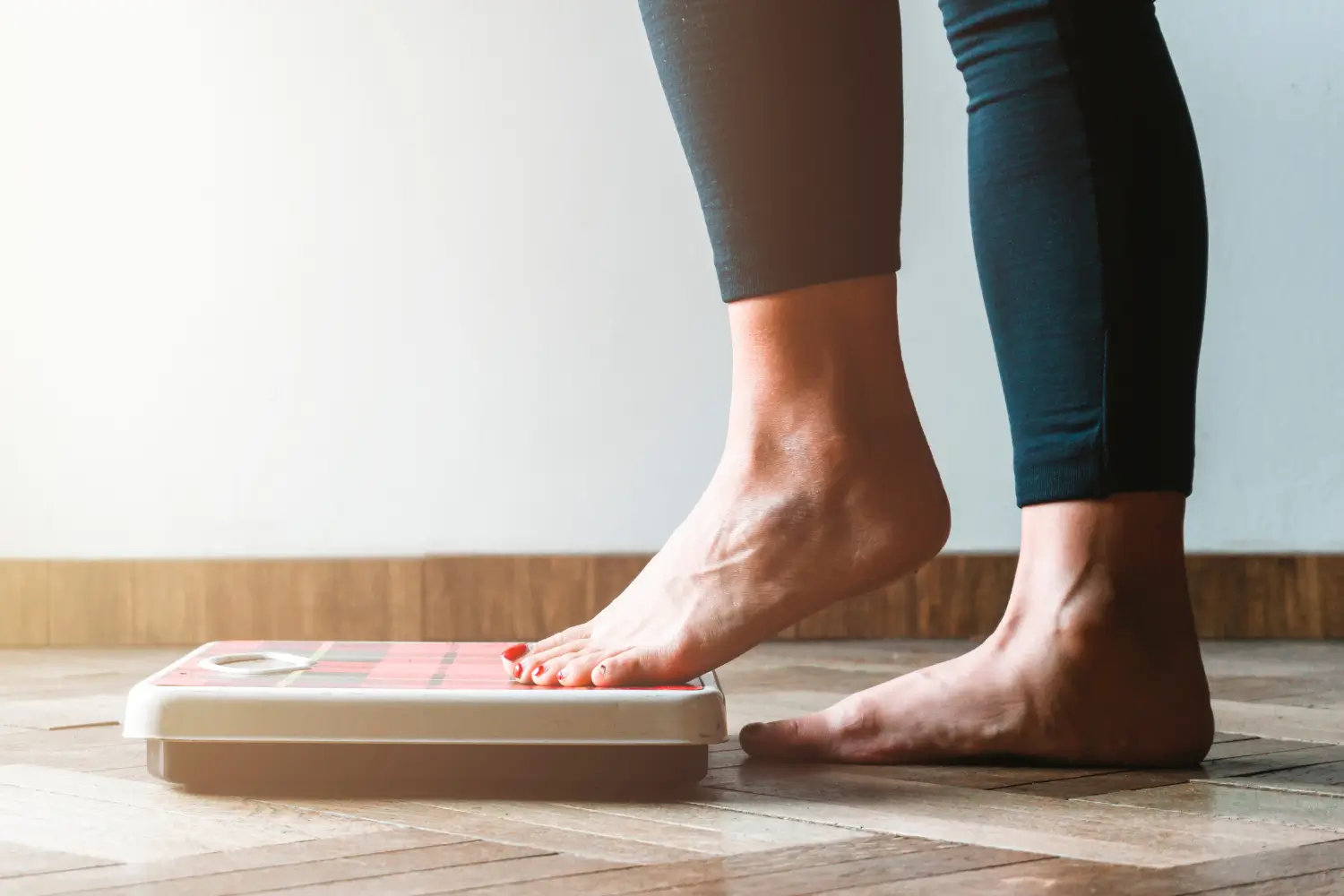 woman stepping onto a scale wondering if she has a slow metabolism